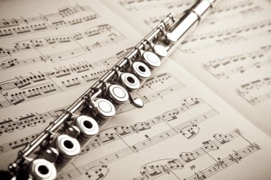 Silver flute on an ancient music score background