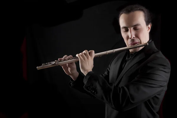 Músico flautista profesional tocando la flauta sobre fondo negro — Foto de Stock