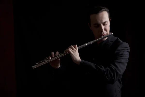 Professional flutist musician playing flute on black background — Stock Photo, Image