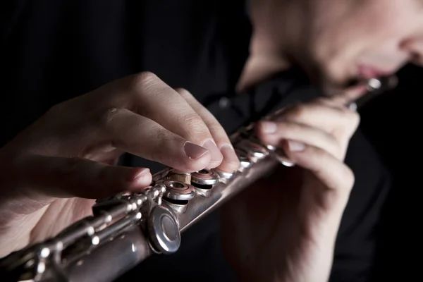 Professional flutist musician playing flute on black background — Stock Photo, Image