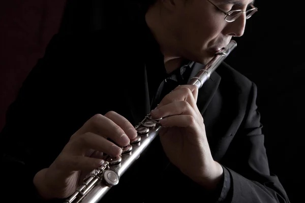 Професійний флейтист музикант грає флейту на чорному фоні — стокове фото