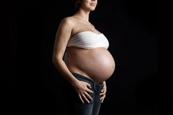 Живот беременной женщины на черном фоне — стоковое фото