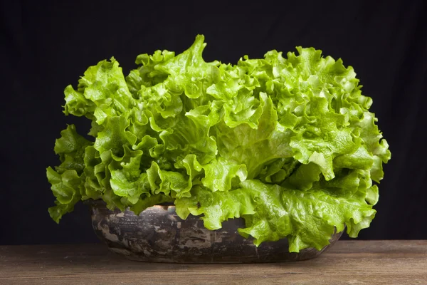 Fresh green lettuce on wooden table on black background — Stock Photo, Image