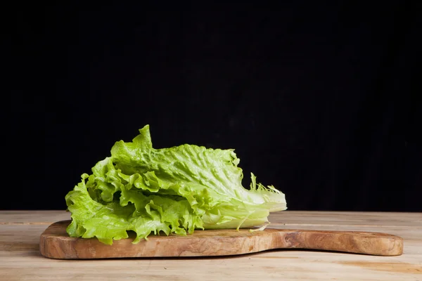 Lettuce leaf on cutting board on black background — Stock Photo, Image