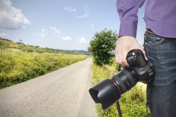 Photographer's hand holding professional digital camera on tusca — Stock Photo, Image