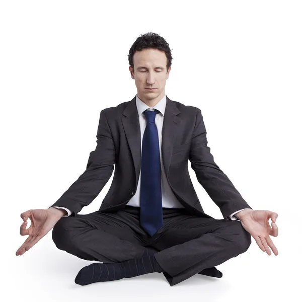 Молодой бизнесмен медитирует в позе лотоса йоги на белом фоне — стоковое фото