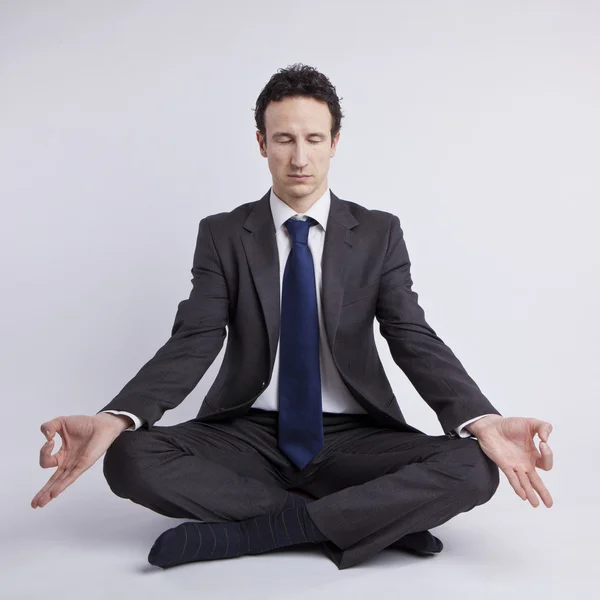 Молодий бізнесмен медитує в йозі лотос позу на білому тлі — стокове фото
