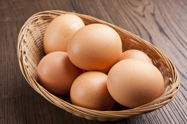 Eieren in een bascket op houten tafel — Stockfoto