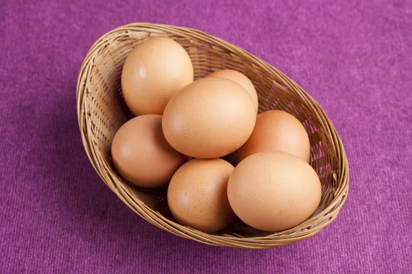 Пасхальные яйца в корзине на фиолетовом фоне — стоковое фото