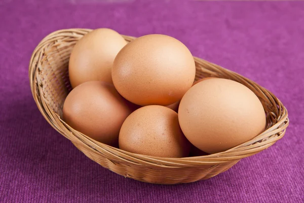 Ovos de Páscoa em um cesto no fundo roxo — Fotografia de Stock