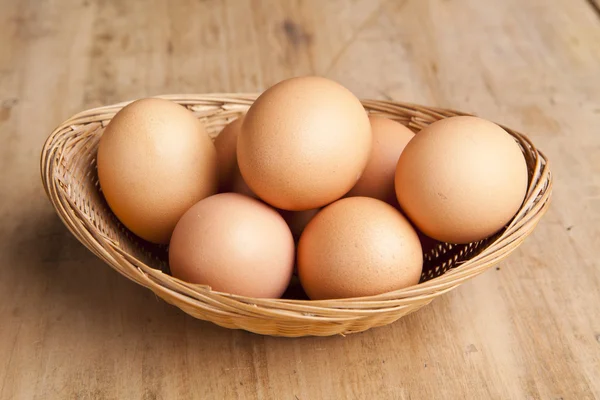 Ovos em um cesto na mesa de madeira — Fotografia de Stock