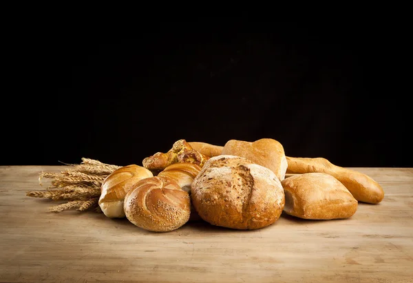 Assortiment van vers gebakken brood op houten tafel — Stockfoto