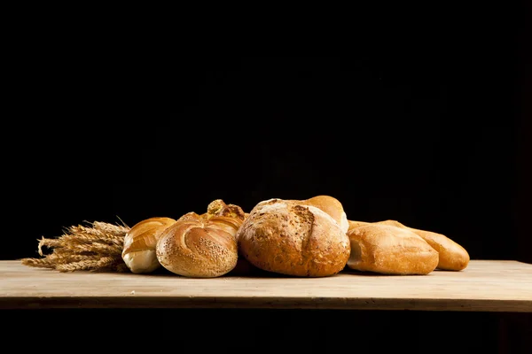 Assortment of fresh baked bread on wood table — Stock Photo, Image