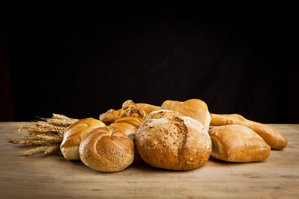 Assortment of fresh baked bread on wood table — Stock Photo, Image