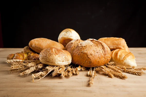 Ahşap masa üzerinde taze pişmiş ekmek çeşitleri — Stok fotoğraf