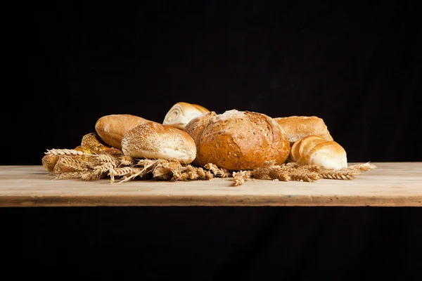 Assortment of fresh baked bread on wood table — Stock Photo, Image