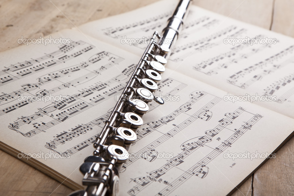 Silver flute on an ancient music score background — Stock Photo