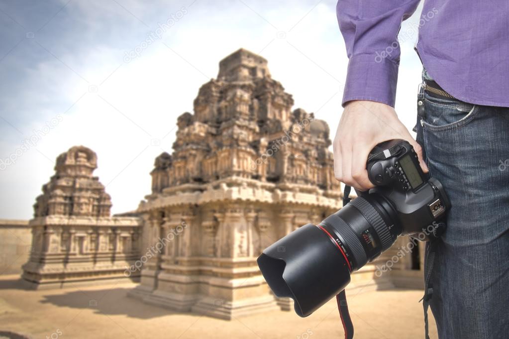 Photographer's hand holding professional digital camera on temple