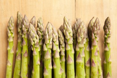 Ahşap arka planda bir sürü taze kuşkonmaz.