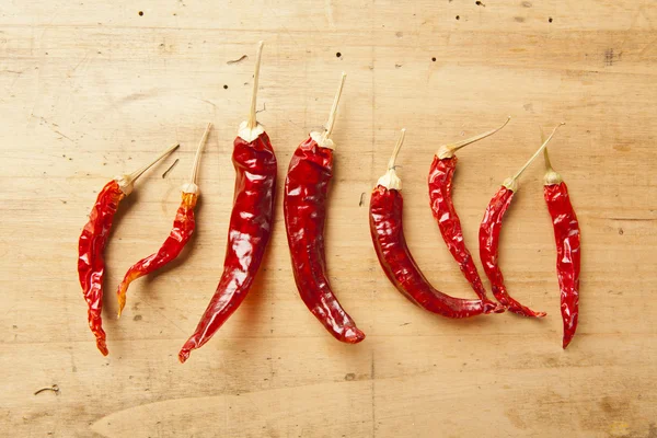 Red hot dry chili peppers over wooden background — Stock Photo, Image