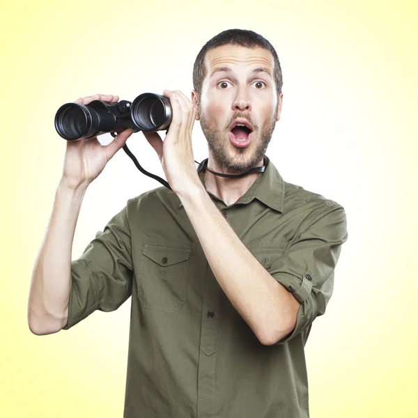 Young man looking through binoculars, surprise face expression — Stock Photo, Image