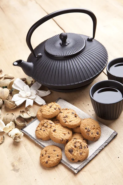 Beautiful teapot with chocolate biscuits on wooden table, delicious breakfast — Stock Photo, Image