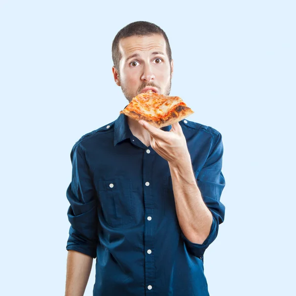 Portrait of a young beautiful man eating a slice of pizza margherita — Stock Photo, Image