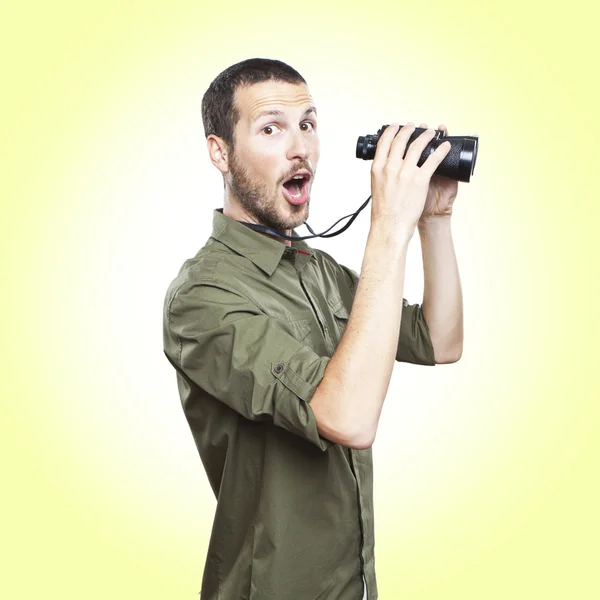 Giovane che guarda attraverso il binocolo, espressione faccia a sorpresa — Foto Stock