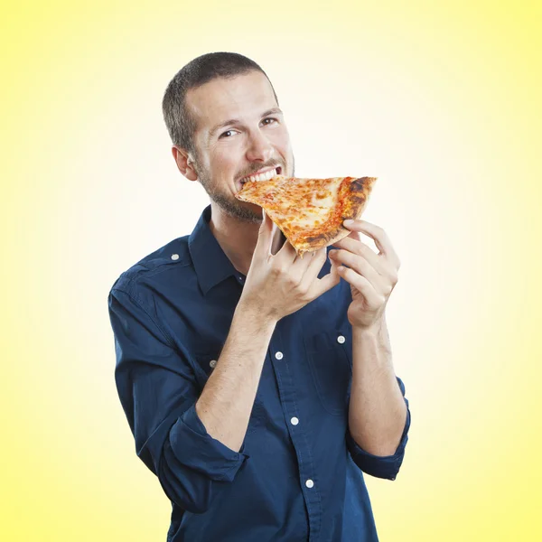 Portrait of a young beautiful man eating a slice of pizza margherita — Stock Photo, Image