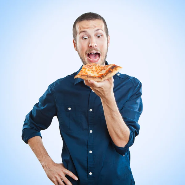 Portrait of a young beautiful man eating a slice of pizza margherita — Stock Photo, Image