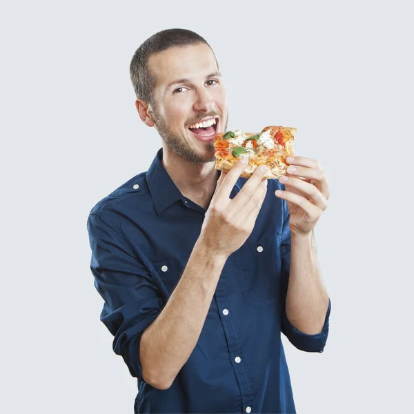 Portrait of a young beautiful man eating a slice of pizza margherita — Stock Photo, Image