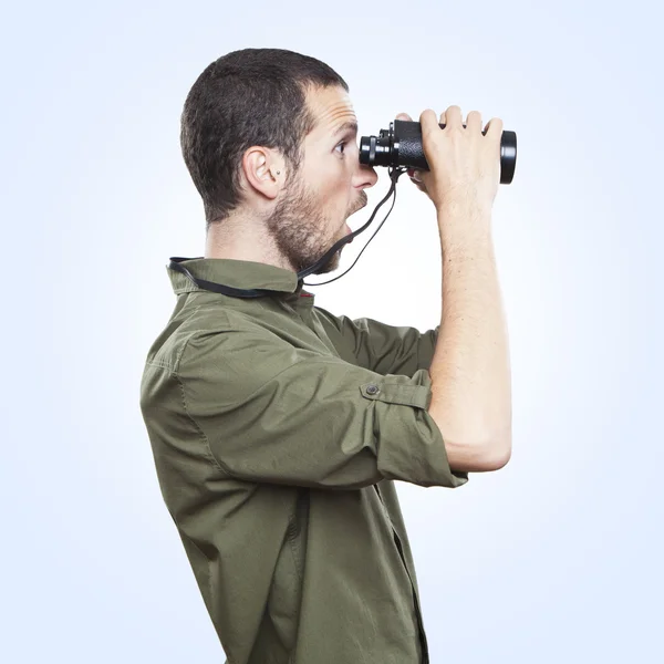 Young man looking through binoculars, surprise face expression — Stock Photo, Image