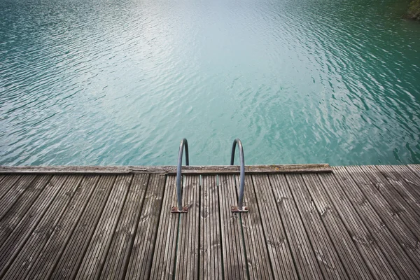 青い湖の水の上の古い木製の桟橋 — ストック写真