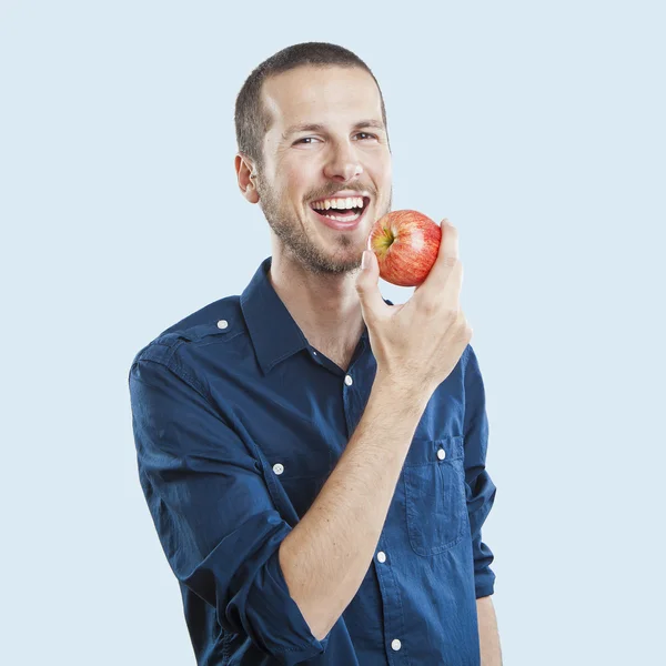 Веселый красивый человек ест яблоко, изолированные на белом фоне — стоковое фото