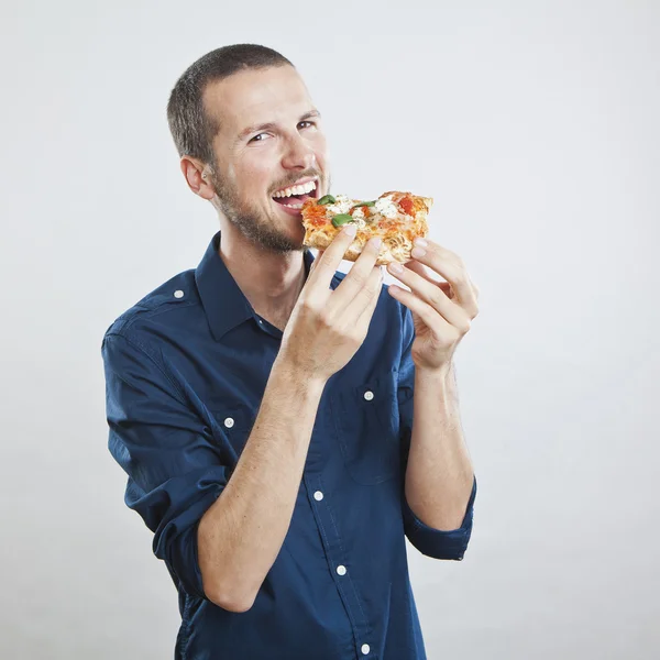 Retrato de um jovem belo homem comendo uma fatia de pizza margherita — Fotografia de Stock