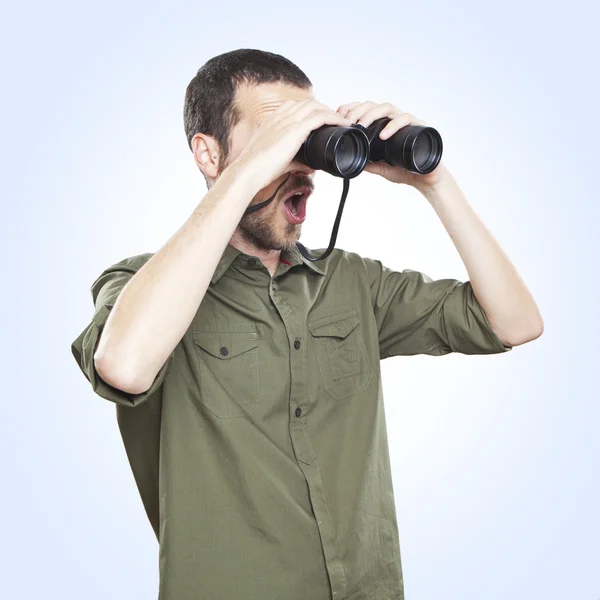 Joven mirando a través de los prismáticos, expresión de la cara sorpresa — Foto de Stock