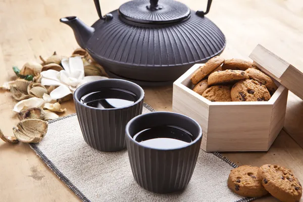 Beautiful teapot with chocolate biscuits on wooden table, delicious breakfast — Stock Photo, Image