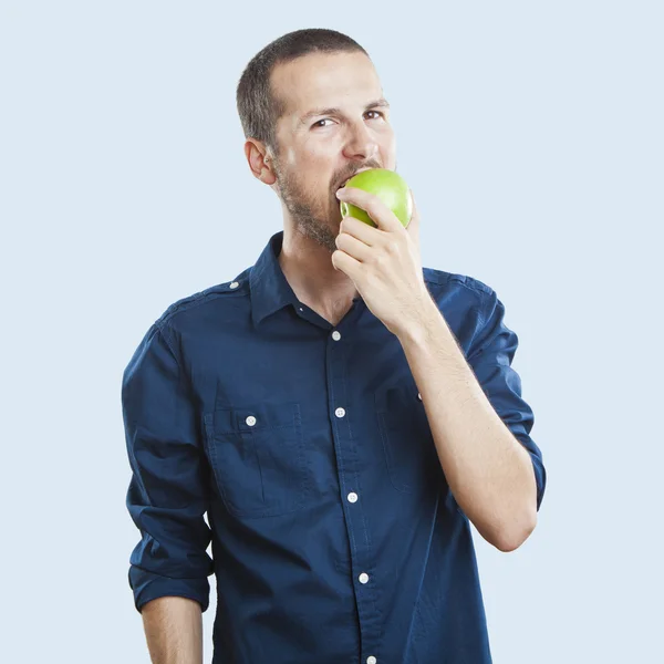 Cheerful beautiful man eating apple, isolated over white background — Stock Photo, Image