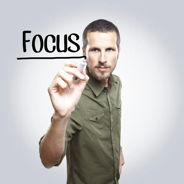 Young casual man writing FOCUS on glass board with marker — Stock Photo, Image