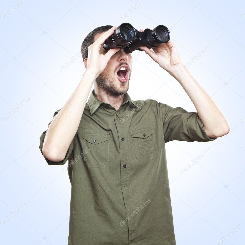 Young man looking through binoculars, surprise face