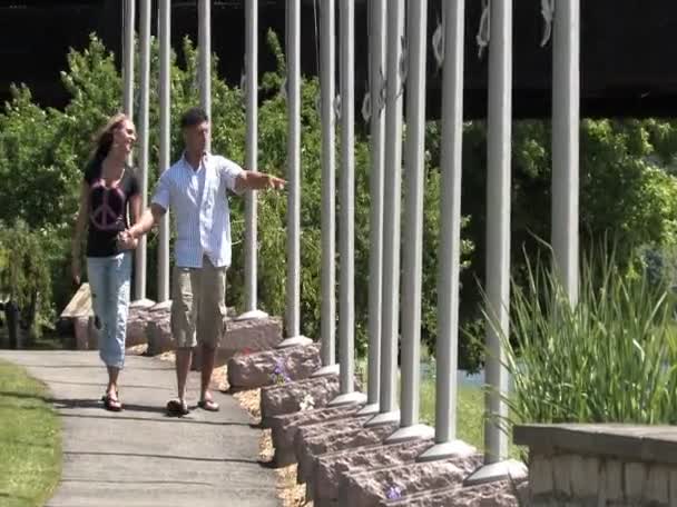Una joven pareja camina por el parque en un día soleado — Vídeos de Stock