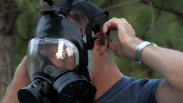 En soldat sätter på sin gas mask i skogen — Stockvideo