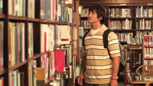 Un estudiante localiza un libro en la biblioteca — Vídeo de stock