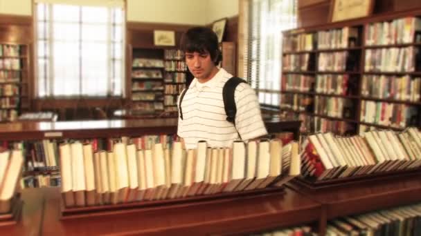 Un estudiante localiza un libro en la biblioteca — Vídeo de stock