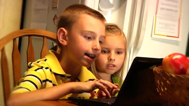 Young children use a laptop in the kitchen — Stock Video