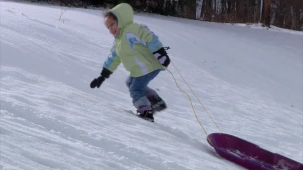 Una niña se deshace del trineo. Movimiento lento . — Vídeo de stock