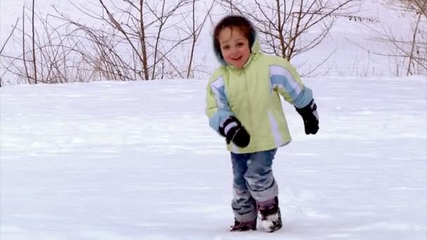 Ένα μικρό κορίτσι που τρέχει προς την κάμερα στο χιόνι. — Αρχείο Βίντεο