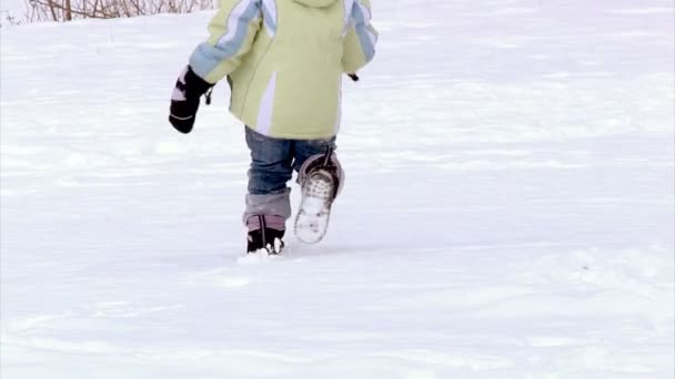 Una niña huye de la cámara en la nieve. Movimiento lento . — Vídeos de Stock