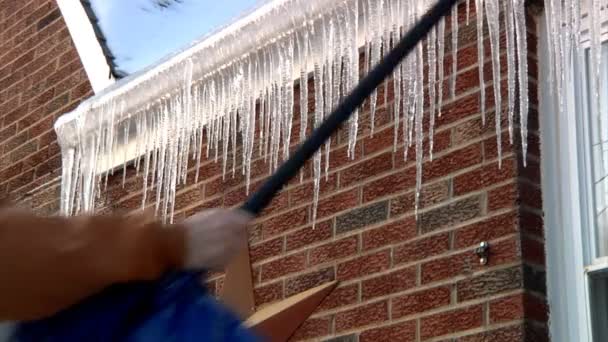 Breaking off dangerous hanging icicles from the roof. — Stock Video