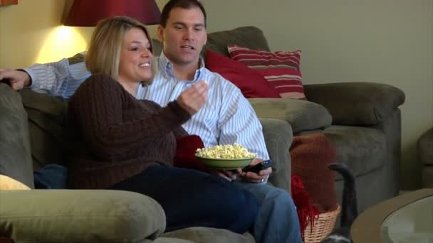 Paar schaut fern, isst Popcorn und streitet über Fernbedienung. — Stockvideo